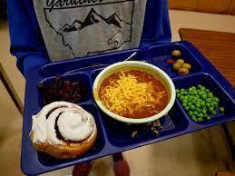 school lunch, blue tray with cinnamon roll, bowl of chili, peas, and green olives.